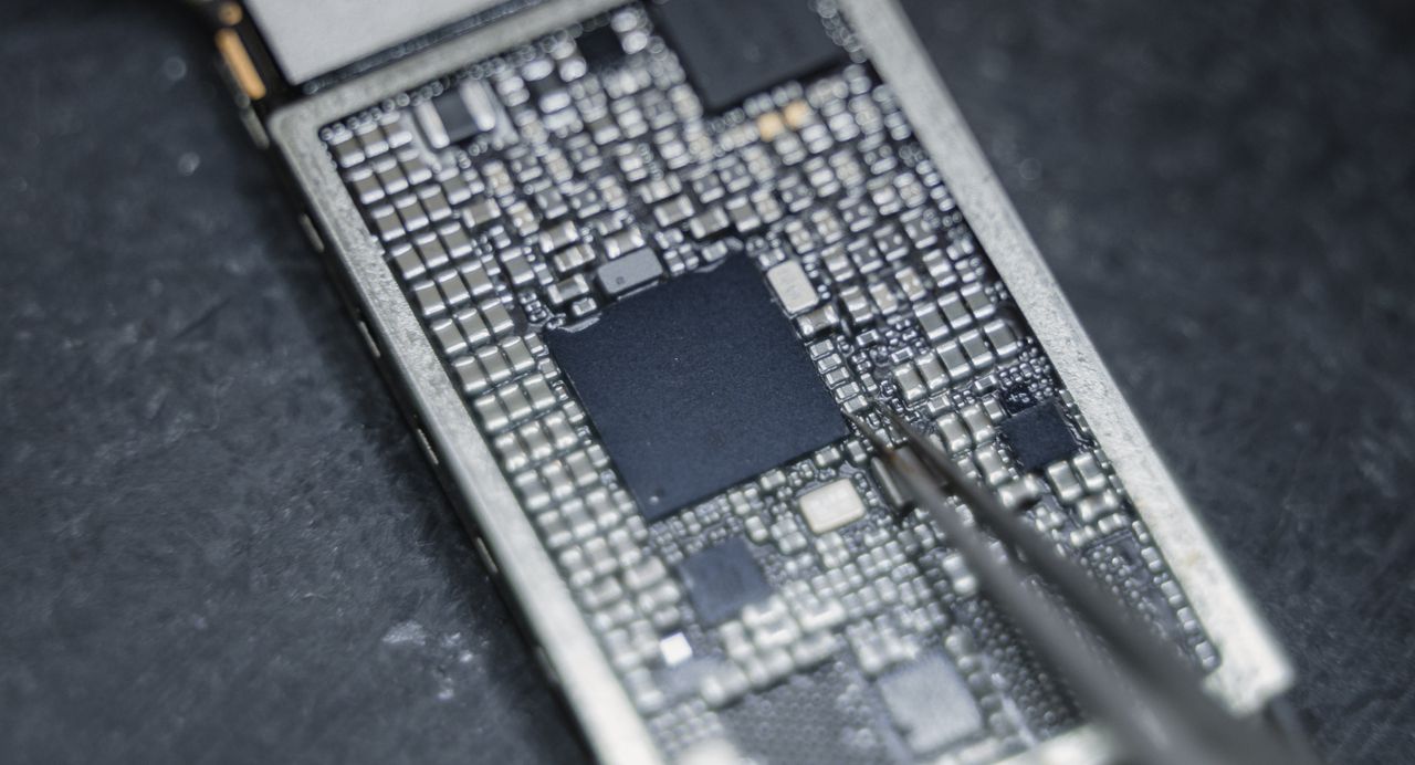Detailed view of a circuit board being worked on with a precision tool, highlighting electronic components.